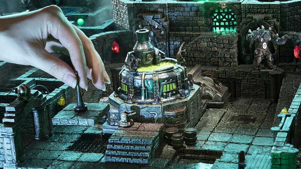 a hand reveals a hidden trap in a dungeon room filled with stone constructs, an acid vat, and barrels