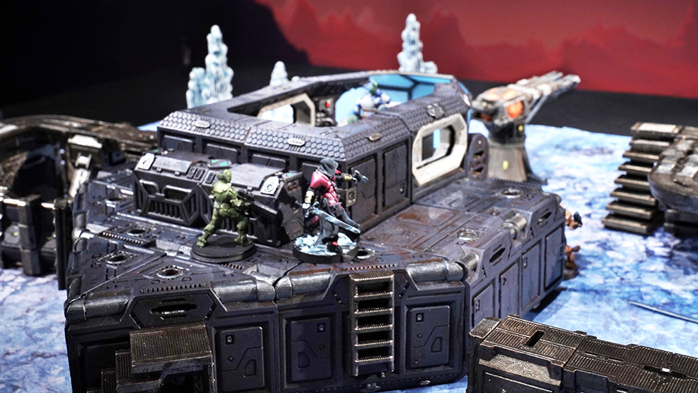 Two miniatures, bracing for attack, hide behind the corner of a bunker on an icy alien planet.